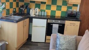 A compact kitchen with a refrigerator, stove, and sink. - glamsflat troccadero (Wolverhampton)