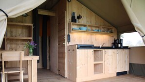 A wooden interior with a dining table, chairs, and a kitchen area with shelves and cabinets.
