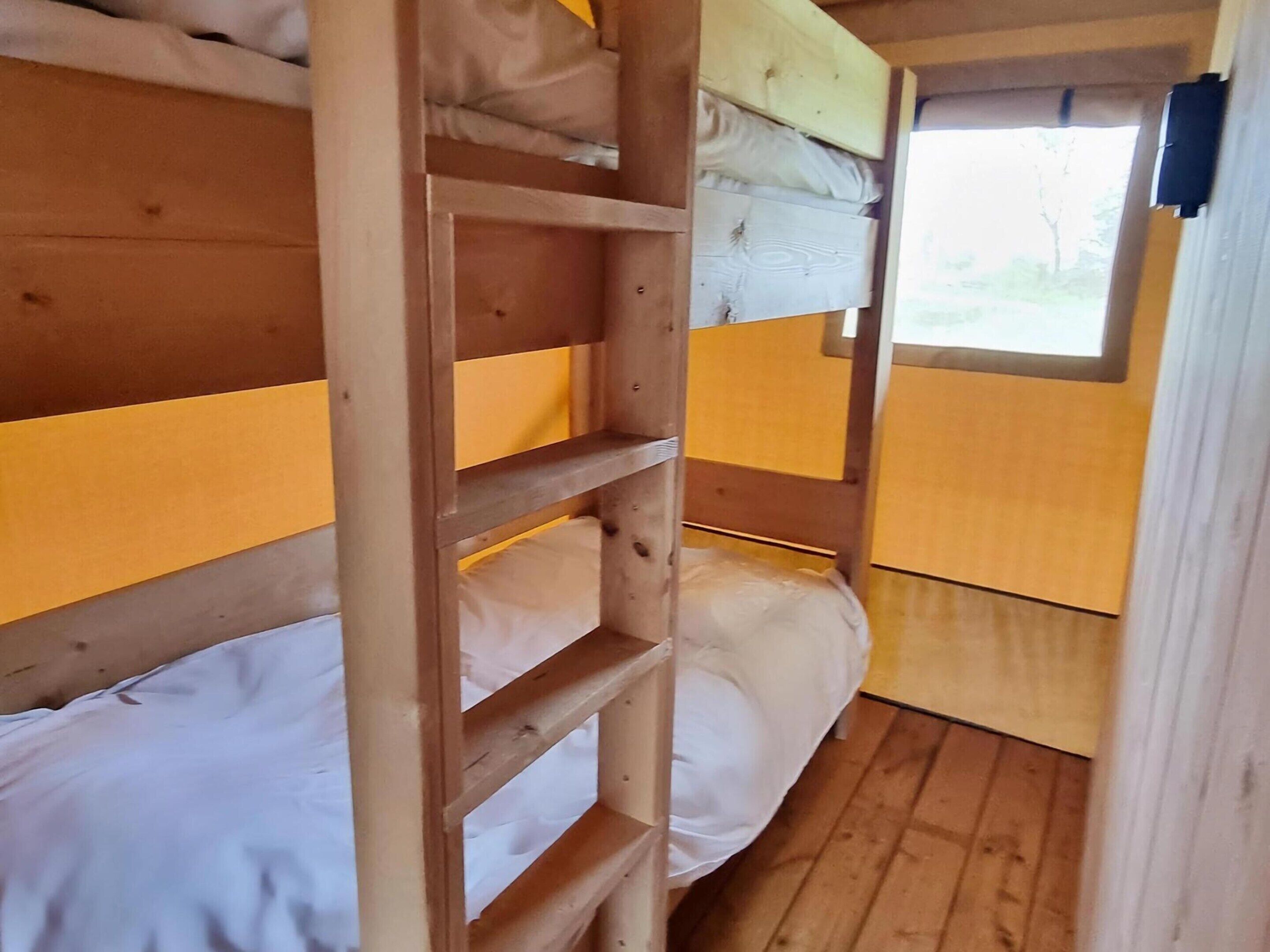 Kerrossängyllä varustettu huone, jossa on puukehikot ja valkoiset vuodevaatteet.