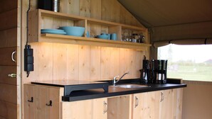 A wooden kitchen with a black countertop, a sink, and shelves above.