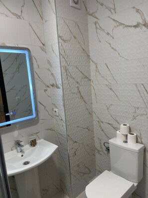 Ein Badezimmer mit Waschbecken, Toilette und einem Spiegel mit Beleuchtung.