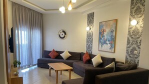 Een woonkamer met een zithoek, een salontafel, een wandklok en een schilderij.