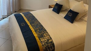 Een hotelkamer met een groot bed, een bedlamp, een spiegel en een hanglamp.