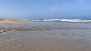 Een strand met heldere lucht en een kalme zee.