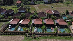 A resort with multiple bungalow-style buildings, each with a swimming pool and surrounded by lush greenery. - Niluh Private Villas (Ubud)