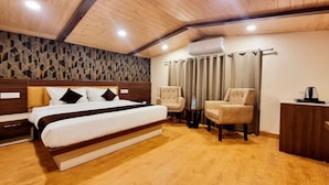 A bedroom with a bed, two chairs, a desk, and an air conditioning unit. - Mountain Valley View By Terraa (Shimla)