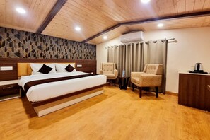 A bedroom with a bed, two chairs, a desk, and an air conditioning unit. - Mountain Valley View By Terraa (Shimla)