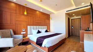 Una habitación de hotel moderna con una cama grande, paneles de madera, un escritorio, una silla y un televisor.