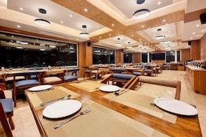 Um restaurante com várias mesas, cadeiras e um bar.