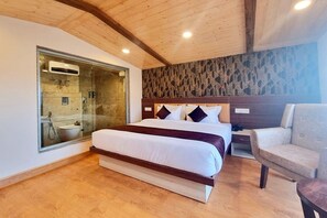 Quarto com uma cama grande, chuveiro em cabine de vidro e teto de madeira.