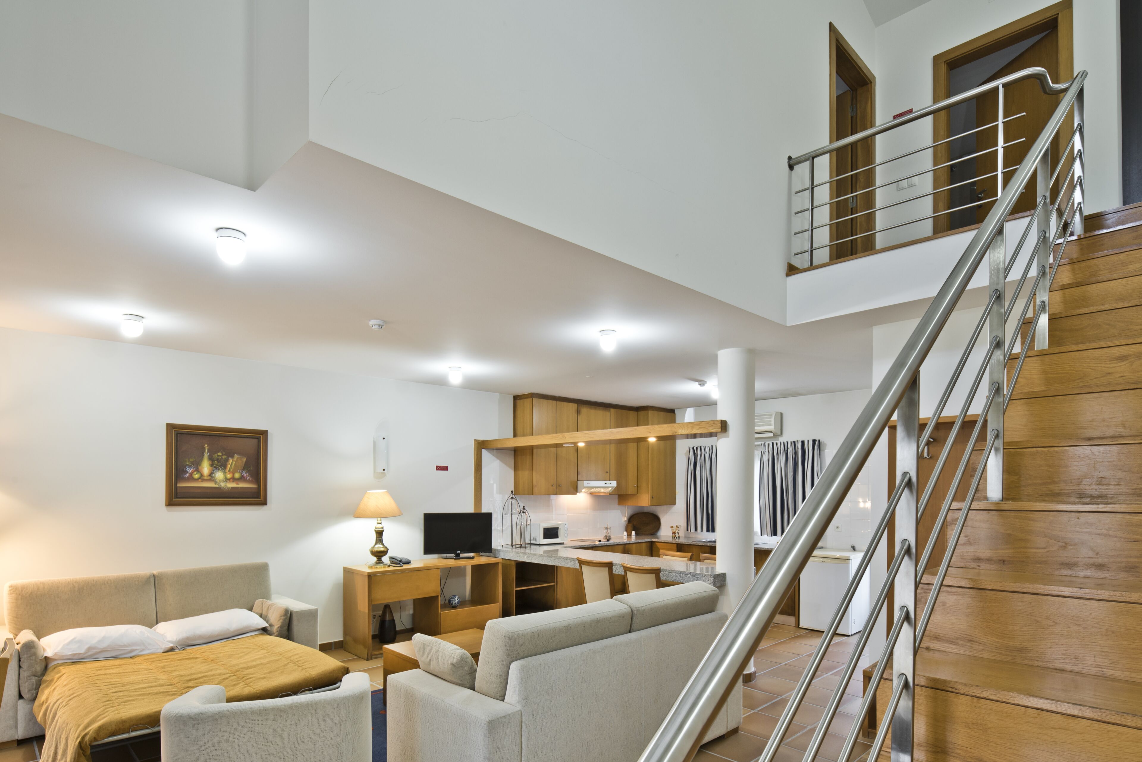 A spacious living area with a sofa, a dining table, and a kitchen in the background.