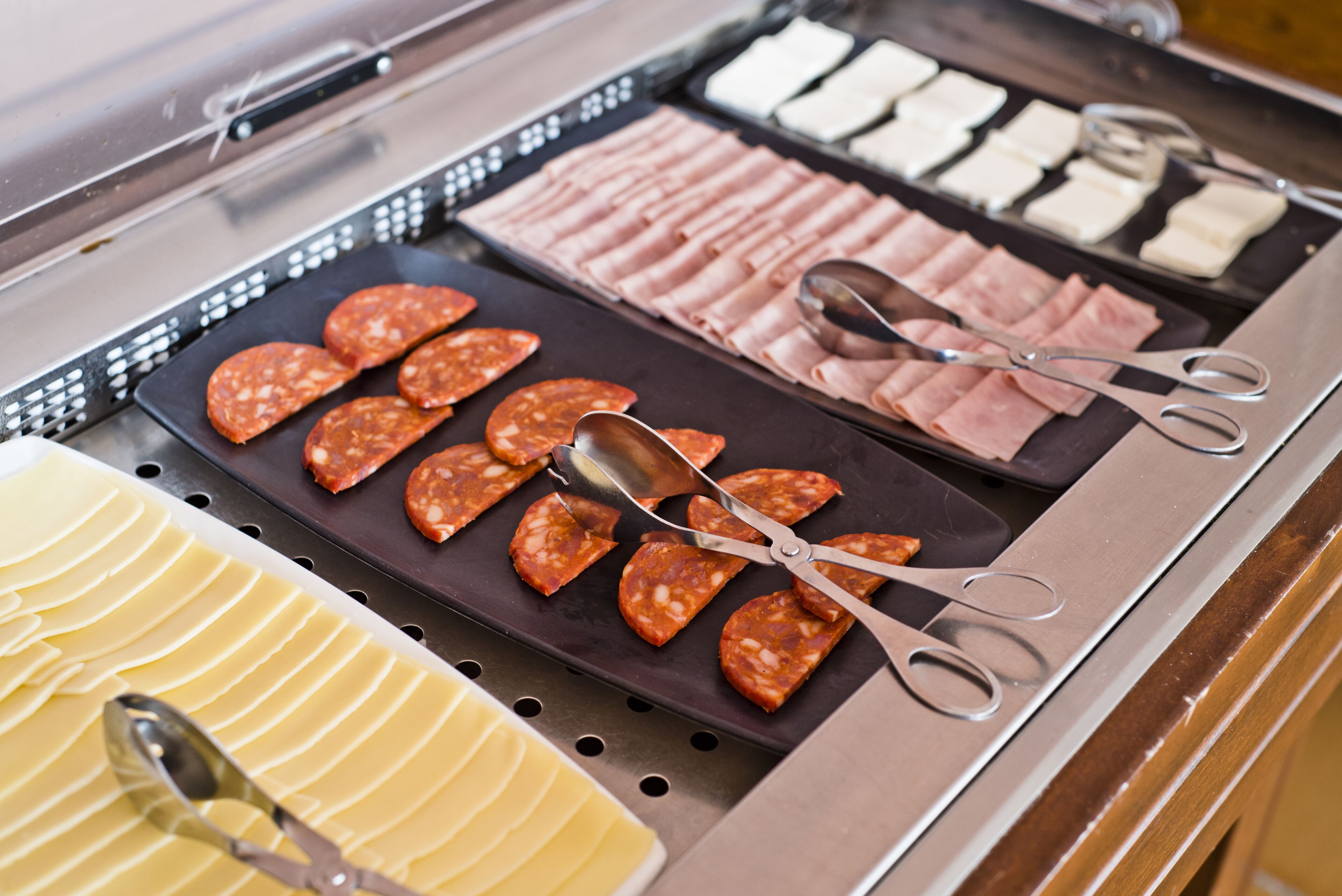 Un bufé con varias carnes frías y quesos.