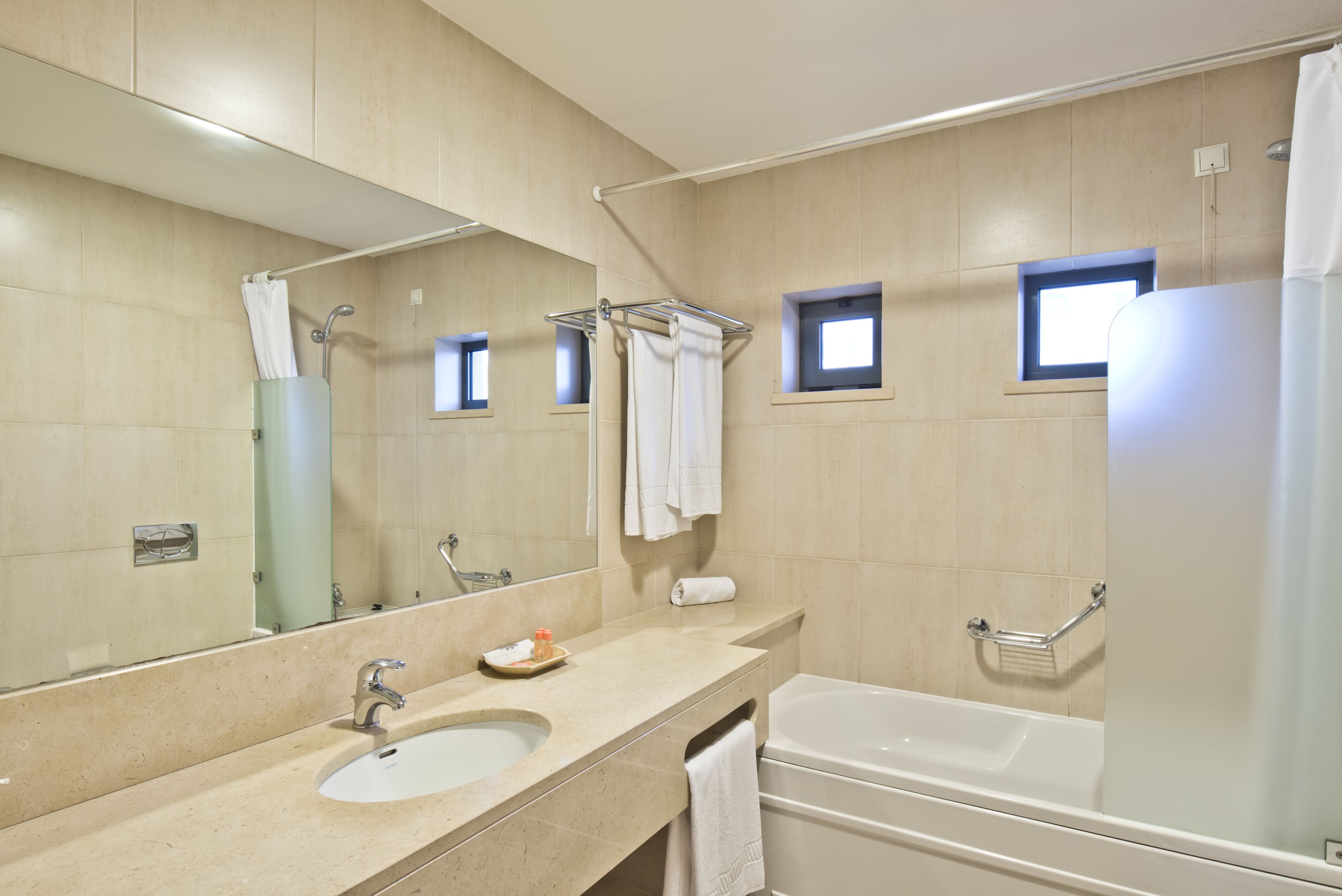 A modern bathroom with a large mirror, a sink, a bathtub, and a shower.