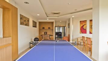 A room with a ping pong table, wooden furniture, and artwork on the walls.