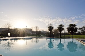 A swimming pool with clear reflections, surrounded by trees and a fence. - Lam Hotel Estarreja (Estarreja)