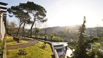 A modern building with a curved roof, surrounded by a landscaped garden with pathways and trees.