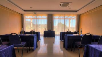 A conference room with tables and chairs, large windows with curtains, and a tiled floor.