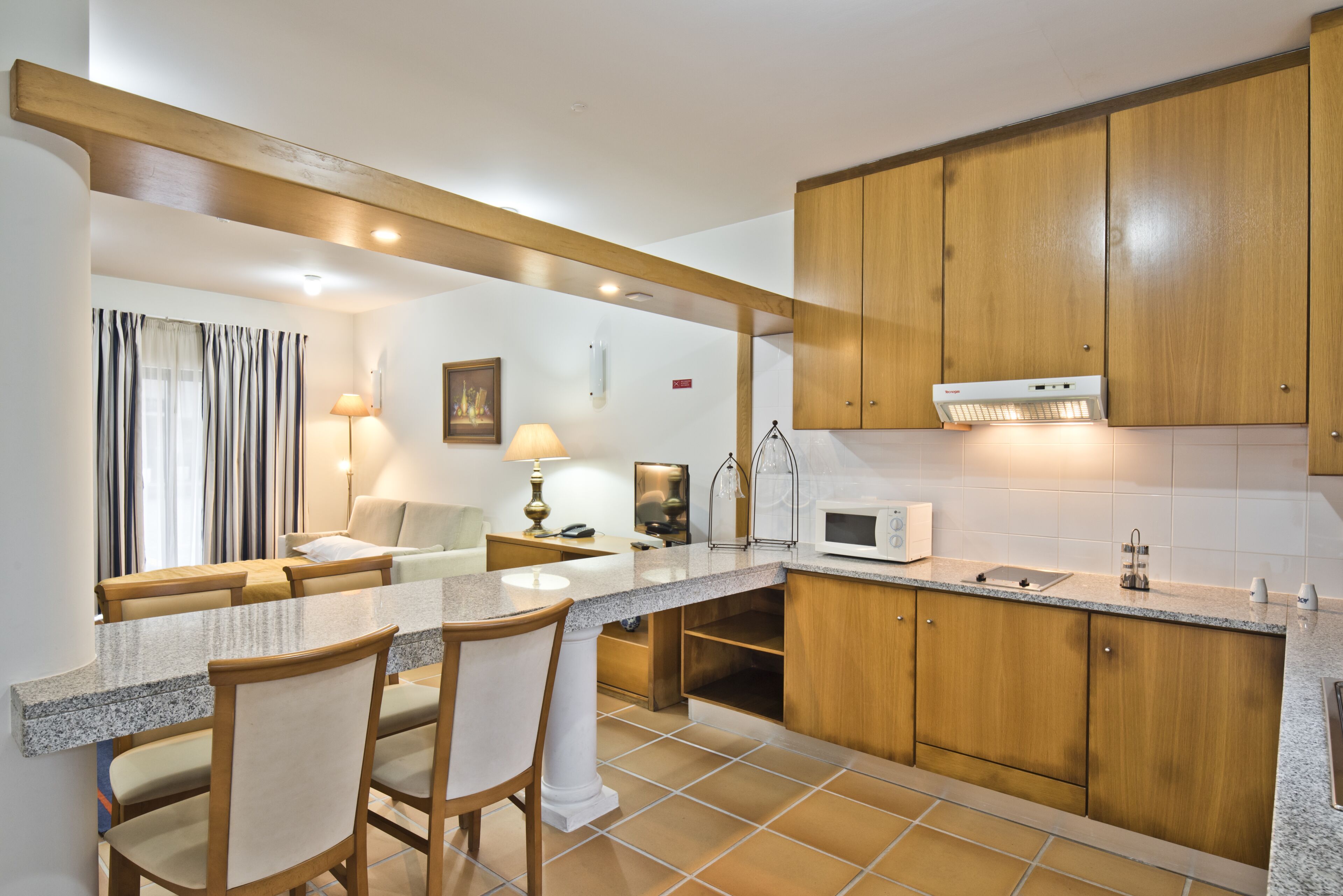 Una cocina moderna con armarios de madera, encimera de granito y un comedor con sillas.