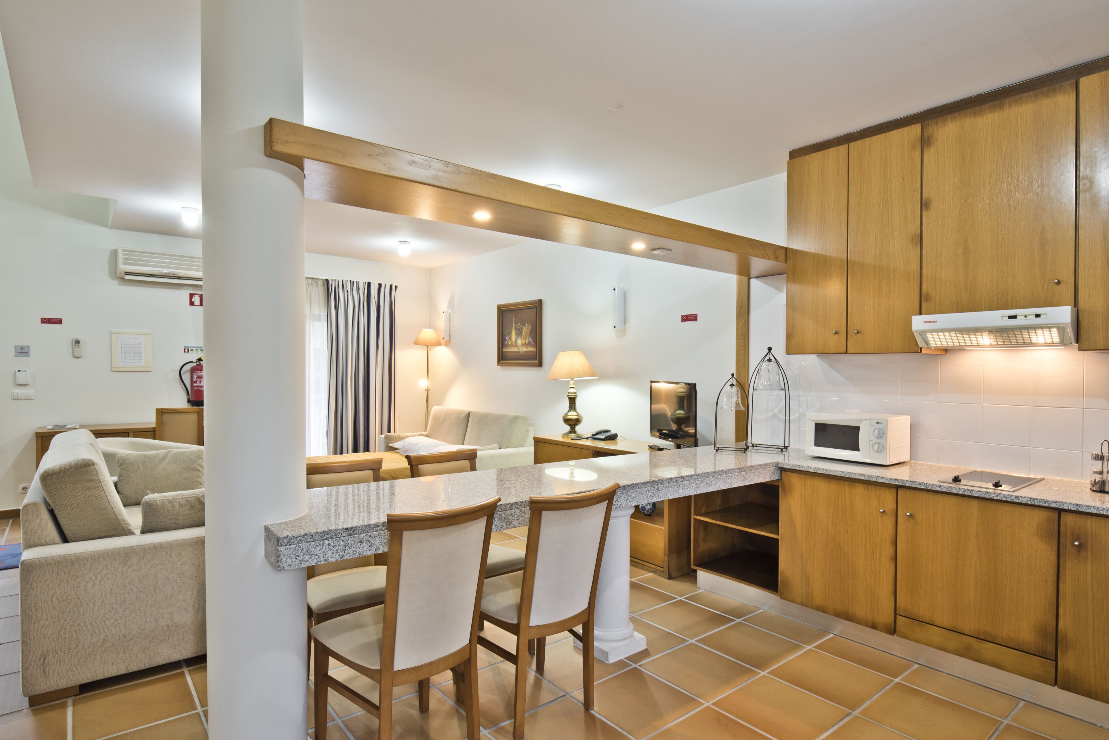 Una cocina moderna con una isla central, armarios de madera y una zona de comedor con sofá y sillas.