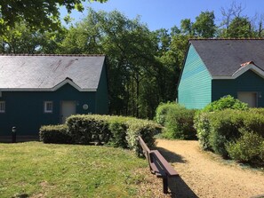 A pathway leading to two green-roofed buildings with a bench in the foreground. - Duplex Cottage With Pool for 4 (Saumur)