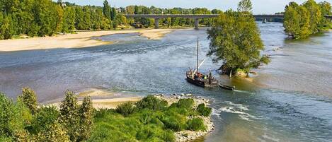 Une rivière où l’on peut naviguer, un pont et une végétation luxuriante.