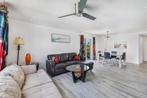 A living room with a sofa, coffee table, and a dining area with chairs and a table.