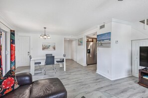 A modern living room with a dining area, a kitchen, and a TV.