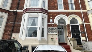 A multi-story building with a prominent 'Clarence House' sign, a bay window, and a staircase leading to the entrance.