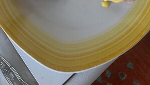 Two eggs benedict dishes on a yellow plate, a croissant, and a white cup on a saucer.