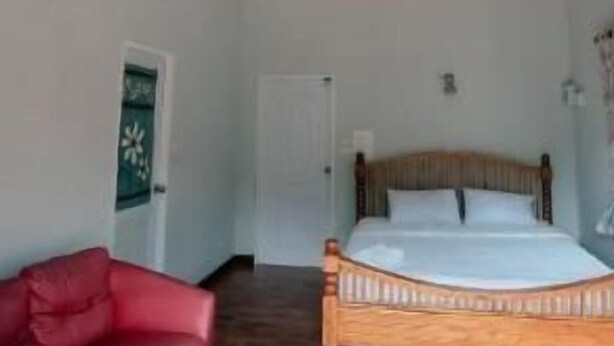 Een slaapkamer met een houten bed, een rode bank en een witte deur.