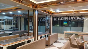 Un interior de restaurante moderno con cabinas y mesas, un amplio ventanal con el nombre 'COVIDIA' a la vista, e iluminación empotrada en el techo.
