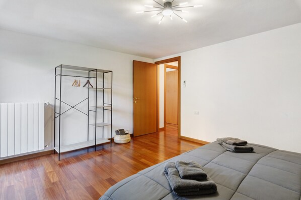 A bedroom with a bed, a wardrobe, a radiator, and a door leading to another room. - Holiday Home 'Villa Cielo Lake Como' with Lake View, Private Terrace and Wi-Fi (Como)