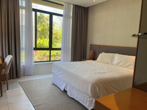 A hotel room with a large bed, a desk, and a window with curtains. - Agréable Villa 1115 (Cam Ranh)