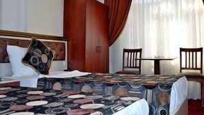 Una habitación de hotel con una cama, un armario de madera, una mesita y una silla.