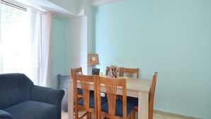 A room with a dining table, chairs, a sofa, and a window with curtains. - A cute & comfortable 2 bedroom apartment (Piraeus)