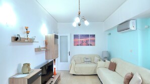 A living room with a sofa, TV, wooden cabinet, and a painting on the wall. - A cute & comfortable 2 bedroom apartment (Piraeus)