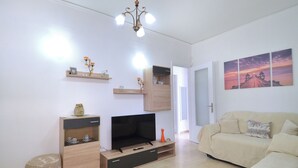 A living room with a TV, wooden entertainment unit, sofa, and artwork on the wall. - A cute & comfortable 2 bedroom apartment (Piraeus)