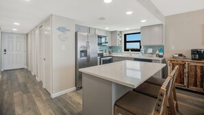 Una cocina moderna con una isla central, electrodomésticos de acero inoxidable y vistas al exterior.