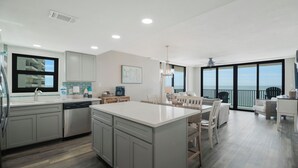 Una cocina moderna con una isla grande, un comedor con vistas y un balcón panorámico.