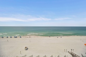 Une plage avec un rivage sablonneux, quelques parasols et un poste de surveillance pour les sauveteurs.