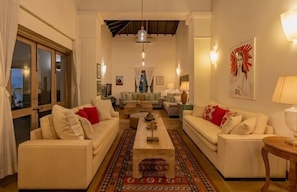 A living room with two sofas, a coffee table, and a patterned rug. - Amã Stays & Trails 70 Vale, Goa (Assagao)