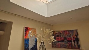 A room with a skylight, two paintings on the wall, and a vase with flowers. - Glams one bedroom apartment (Wolverhampton)