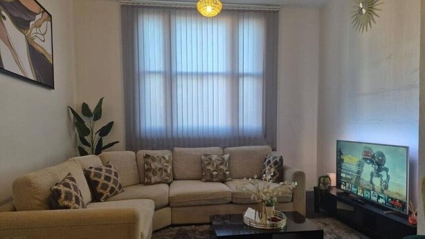 A living room with a sofa, a coffee table, a TV, and a window with curtains. - Glams one bedroom apartment (Wolverhampton)