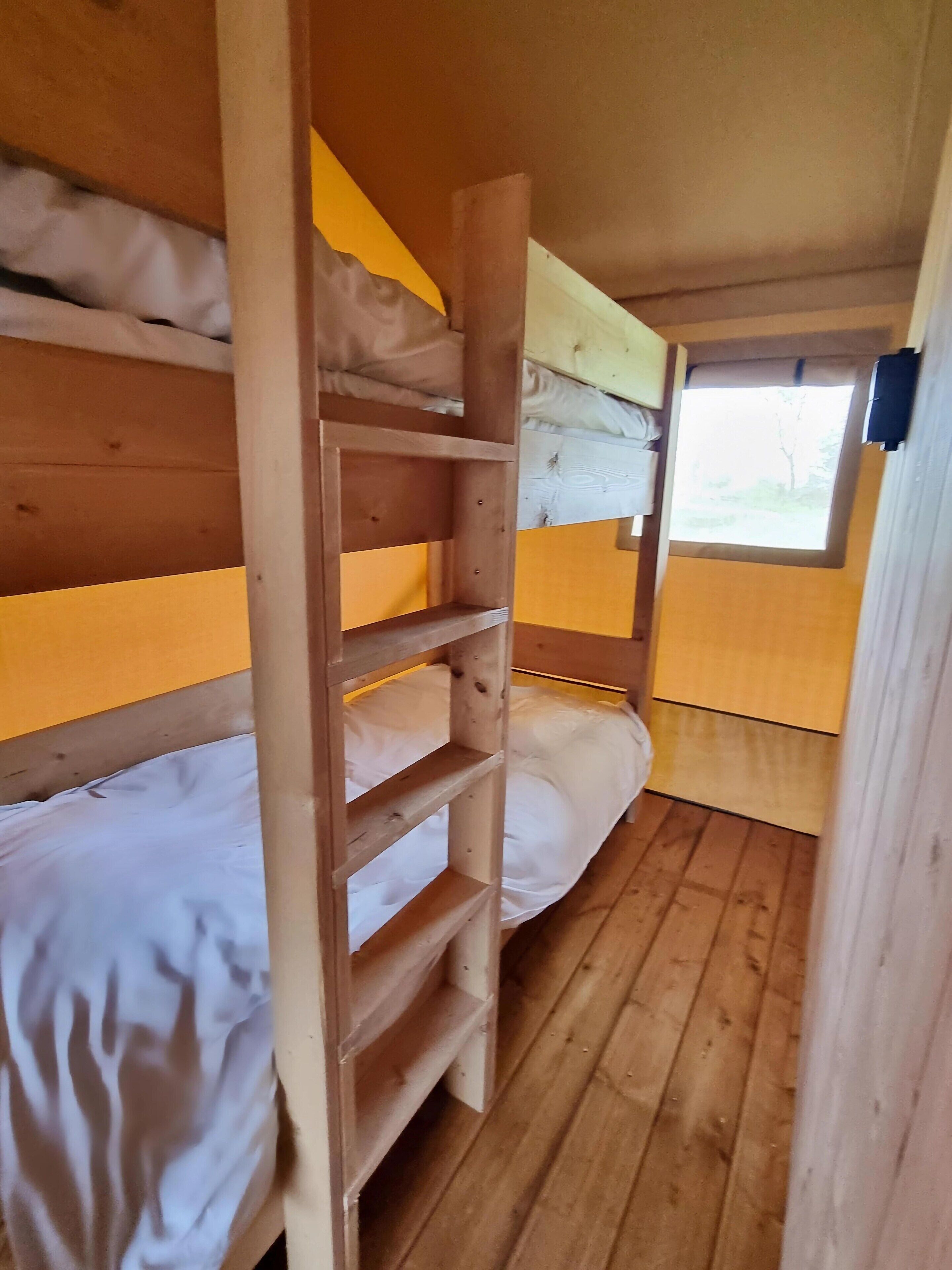 Camera con letti a castello, pareti in legno e una finestra.