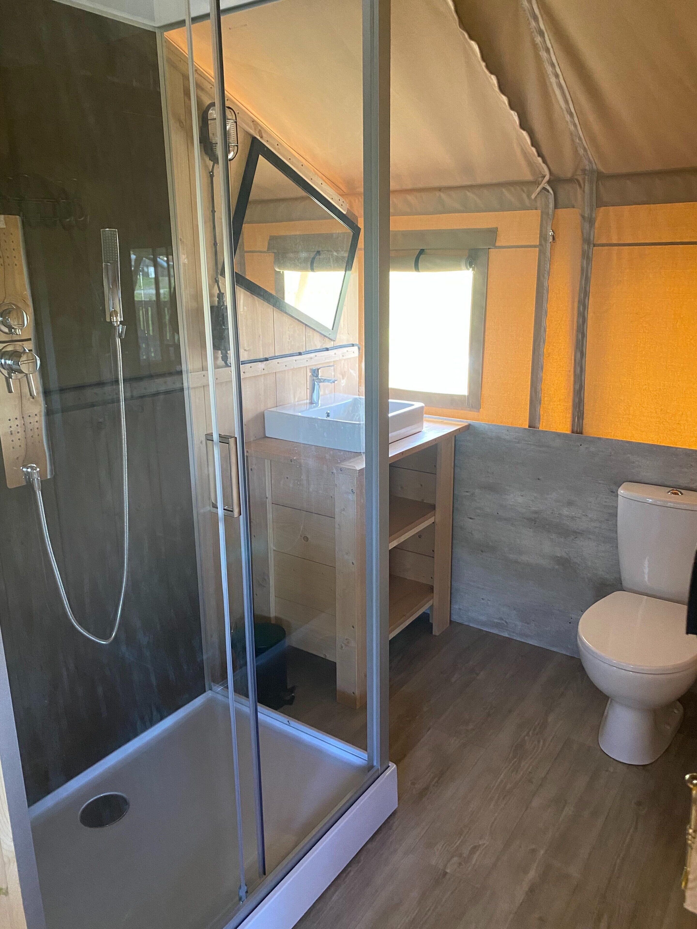 Une petite salle de bain dotée d’une douche à parois de verre, d’un lavabo et de toilettes.