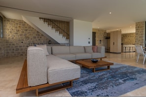 A modern living room with a sectional sofa, a wooden coffee table, and a staircase. - Messinian Nest (Pylos-Nestoras)