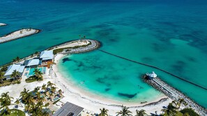 An aerial view of a resort with a beach, clear turquoise waters, and a pier. - Paradise Cove Cap Cana Monthly Rental (La, Altagracia)