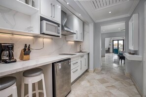 A modern kitchen with white cabinets, a built-in microwave, a stainless steel range hood, and a dishwasher. - Paradise Cove Cap Cana Monthly Rental (La, Altagracia)