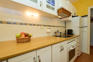 A kitchen with white cabinets, a wooden countertop, a sink, a stove, and a refrigerator. - Sunny Haven at the Village Square (Palafrugell)