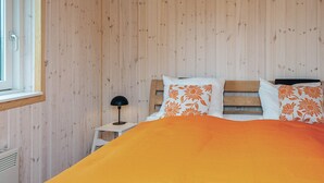 Ein Zimmer mit Holzwänden, einem Bett, einem Nachttisch und einem Fenster.